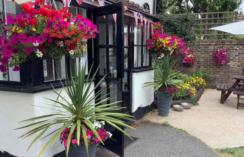 Garden and pub entrance with pretty flower baskets.